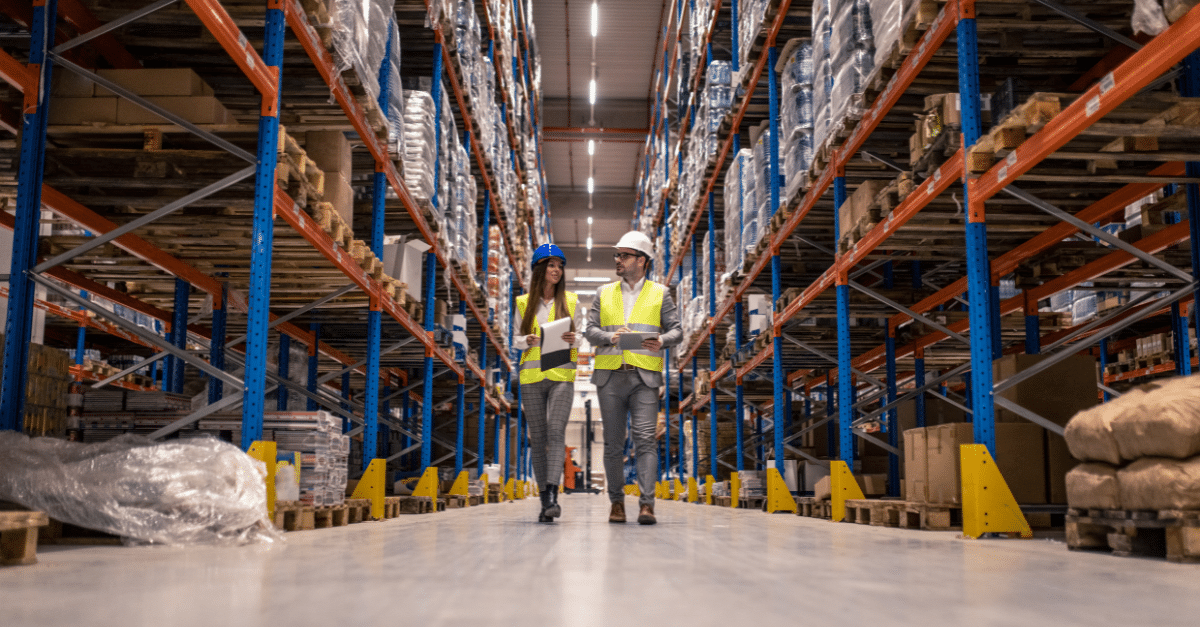 Two people walking through a warehouse.