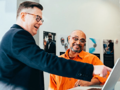 Two men standing in front of a computer.