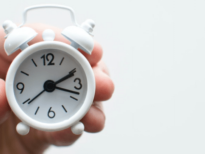 A person holding an alarm clock on a white background.