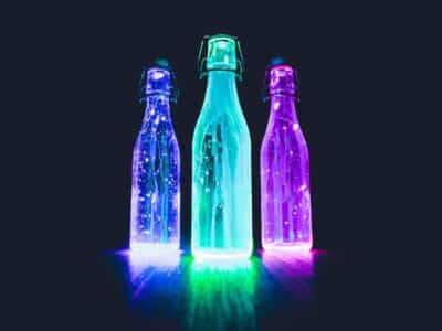Three light up water bottles on a dark background.