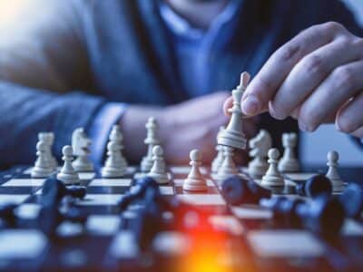 A man is playing chess on a chess board.