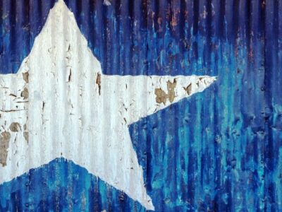 A Texas flag painted on a corrugated metal wall.