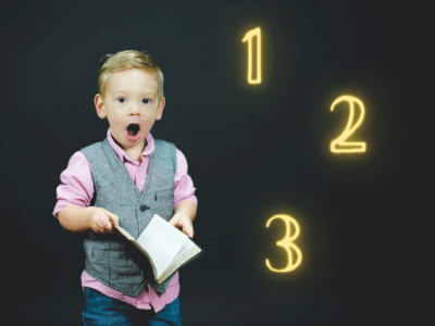 A young boy holding a book with numbers on it.