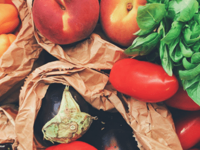 A bunch of fruits and vegetables in brown paper bags.