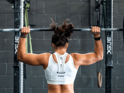 A woman lifting a barbell in a gym.