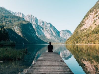 A man sitting on a dock overlooking a lake.