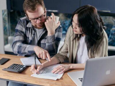 A man and woman are sitting at a table and talking on the phone.