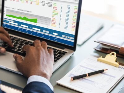 A man is working on a laptop with financial data on it.