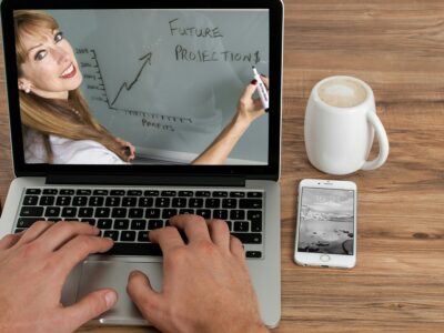 A woman is using a laptop with a chalkboard on it.