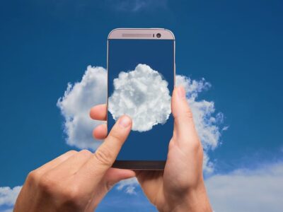 A hand holding a smartphone with a cloud on it.