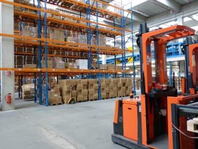 Two orange forklifts in a warehouse.