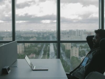 A man sitting at a desk with a laptop in front of a window.