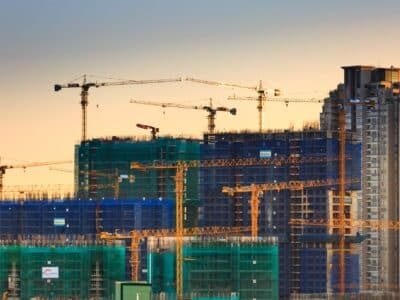 Construction cranes on a construction site at sunset.