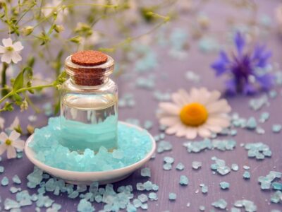 A bottle of sea salt and flowers on a table.