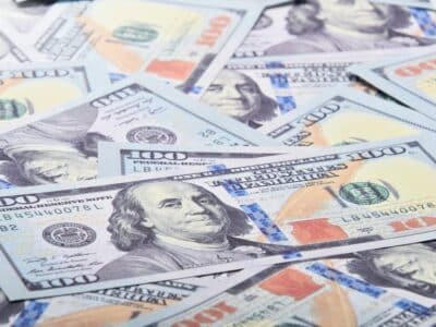 A pile of us dollar bills on a white background.