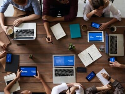 A group of people sitting around a table with laptops.