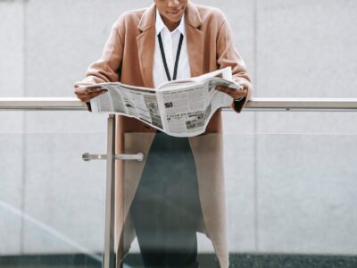 A business woman reading a newspaper on a balcony.