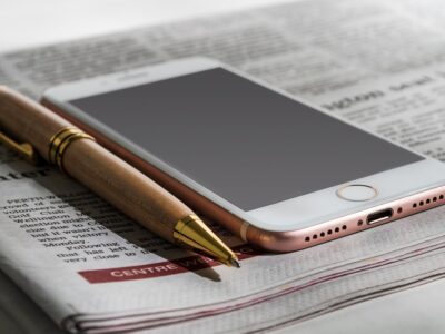 A phone and a pen on top of a newspaper.