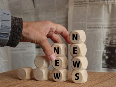 A person holding wooden blocks with the word news on them.