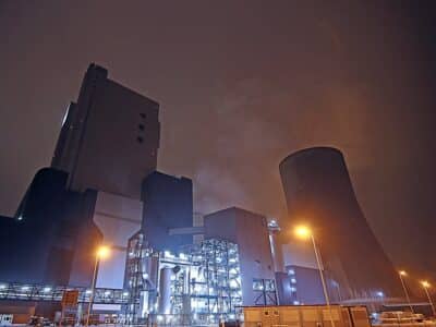 A night scene with a cooling tower in the background.