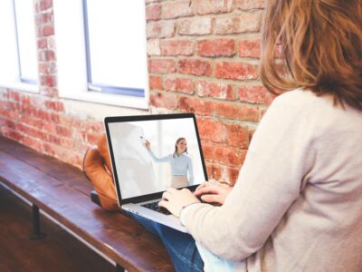 A woman sitting on a bench with a laptop.