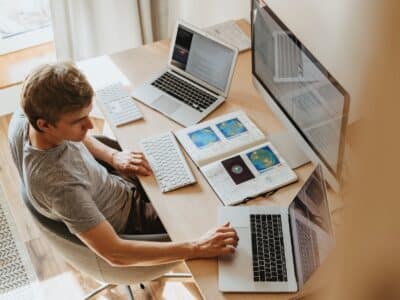 A man sitting at a desk with several laptops and monitors.