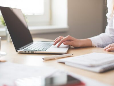 A woman typing on a laptop at a desk.