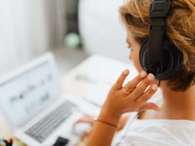 A woman is listening to music while working on her laptop.