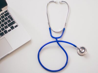 A stethoscope next to a laptop on a white table.