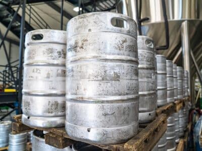 Kegs of beer sitting on pallets in a brewery.