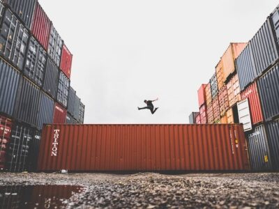 A man jumping in front of shipping containers.