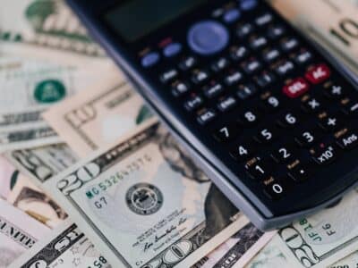 A calculator sits on top of a pile of money.