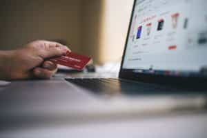 A person holding a credit card on a laptop.