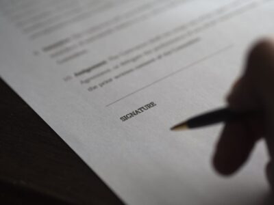 A person signing a document with a pen.