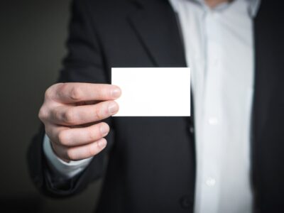 A man in a suit holding a blank business card.