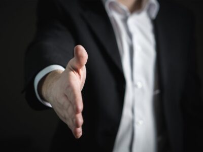 A businessman in a suit is handing someone a handshake.