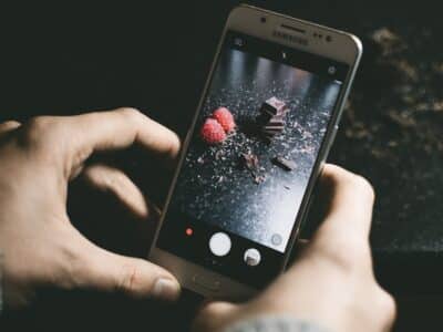 A person is holding a smartphone and taking a picture of chocolate.