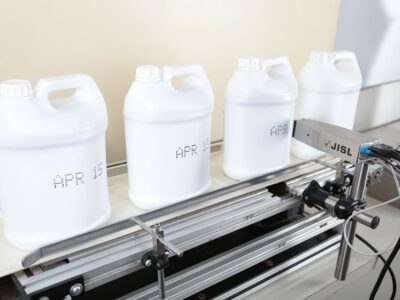 Four white jugs sitting on a conveyor belt.