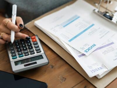 A woman using a calculator and a pen on a desk.