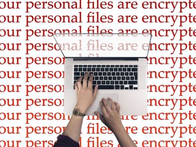 A person typing on a laptop with the words personal files are encrypted.