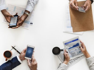 A group of business people using their phones and tablets at a table.