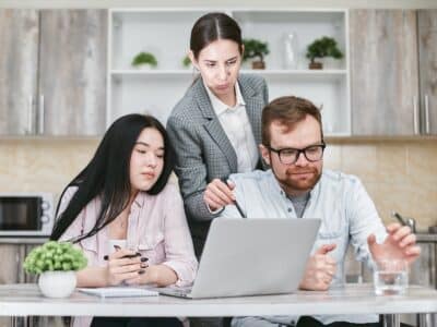 A group of people sitting around a table looking at a laptop.