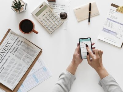 A woman is using a smart phone while sitting at a desk.