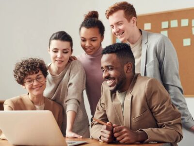 A group of people looking at a laptop in an office.