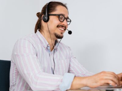 A man wearing a headset while working on a laptop.