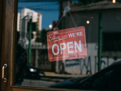 A sign that says we're open hanging from a window.