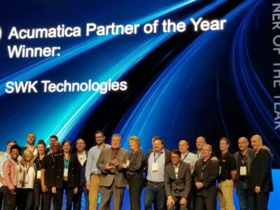 A group of people standing on a stage with the words swc technologies partner of the year.