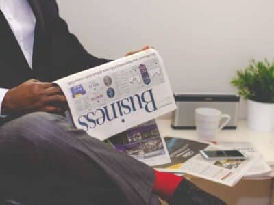 A man in a suit reading a newspaper.