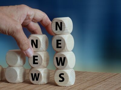 A hand is putting wooden blocks with the word news on them.
