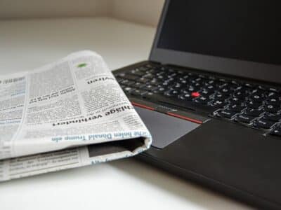 A laptop computer with a newspaper on it.